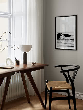 Svartinramad svartvit bild av en valstjärt ovanför ett skrivbord i ett ljust rum