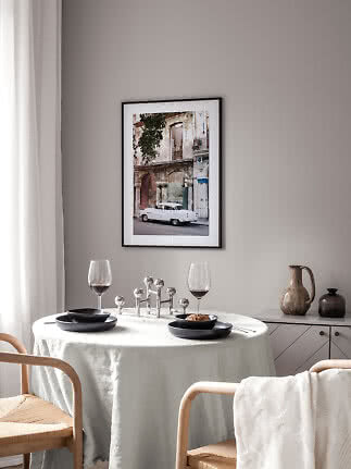 Framed photo art of a white vintage car by a weathered building above a set dining table