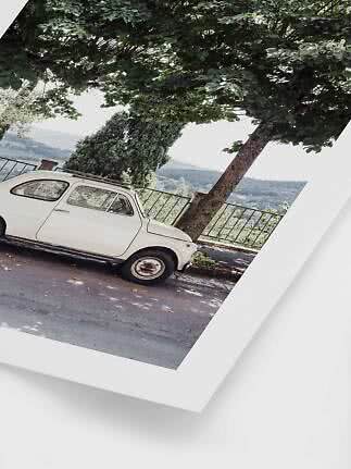 Poster of a white vintage car parked under a large tree overlooking hills
