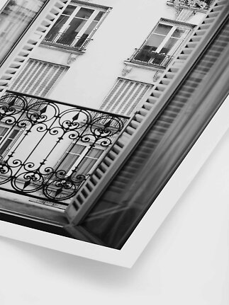 Black-and-white photo of a balcony and windows on a classic building seen through open shutters