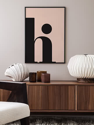 Gerahmtes abstraktes Poster mit schwarzer grafischer Form auf rosigem Hintergrund über Holzsideboard