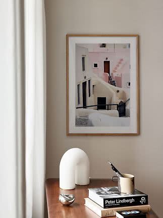 Framed photo print of pastel buildings above a wooden table with books and decor