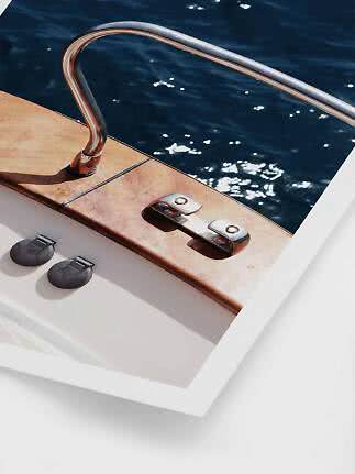 Two black round adhesive pads shown in front of a photo of a boat edge with metal rail by the water