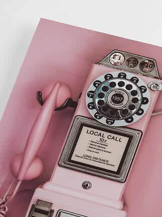 Teléfono público retro rosa con auricular sobre fondo rosa
