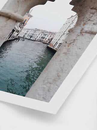 Framed photo of a canal lined with buildings, seen through a stone opening