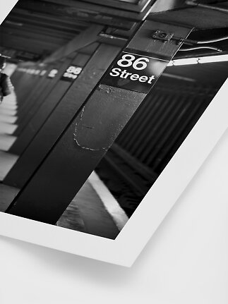 Photo en noir et blanc d’un quai de métro avec panneau 86 Street sur un pilier