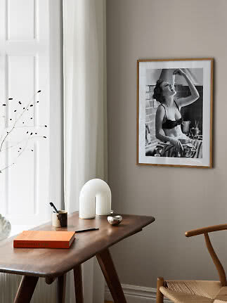 Indrammet sort-hvid foto på beige væg over træbord ved vindue