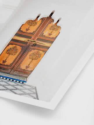 Decorative old wooden door with floral motifs and mosaic border on white wall