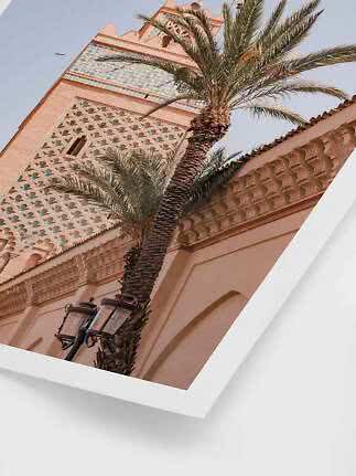 Palm trees in front of an ornate pink tower with blue-green tiles, viewed from below