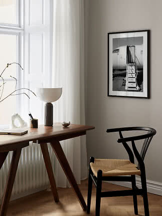 Sort indrammet sort-hvid plakat af flytrappe hænger over skrivebord og stol i lyst rum.