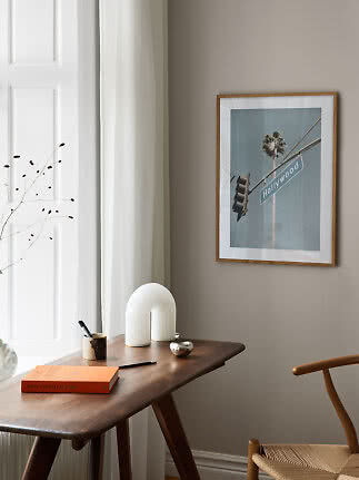 Framed Hollywood poster above a wooden desk in a bright, modern room