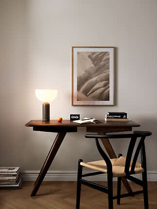 Dunkler Holzschreibtisch mit leuchtender Tischlampe, Buch, Stuhl und gerahmtem Landschaftsbild