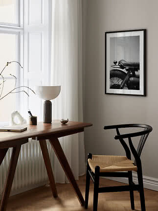 Spazio di lavoro minimalista con scrivania in legno, sedia nera e stampa moto in bianco e nero.