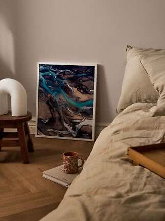 Gerahmter Kunstdruck mit Luftaufnahme blauer Flussläufe, an eine Schlafzimmerwand gelehnt