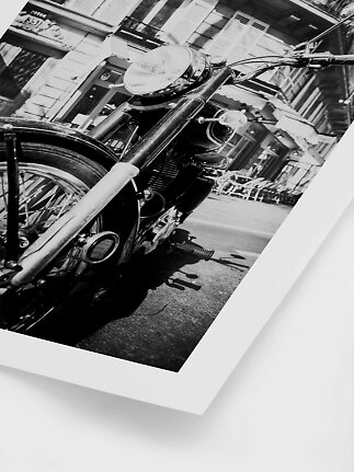 Sort-hvid foto af en klassisk motorcykel parkeret på en bygade, set tæt forfra