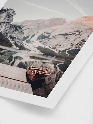 Framed photo of a rowboat by a wooden dock on a calm mountain lake