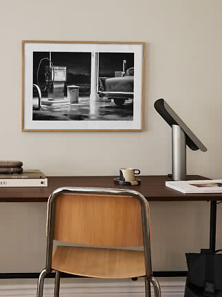 Mesa com cadeira, luminária e foto em preto e branco emoldurada na parede