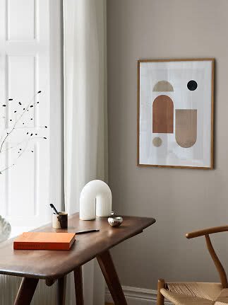 Abstrakt plakat i træramme over skrivebord i lyst, minimalistisk hjørne