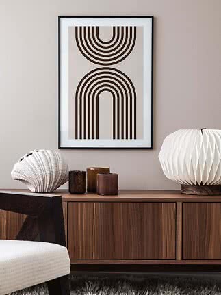 Framed abstract print with brown curved lines above a wooden sideboard