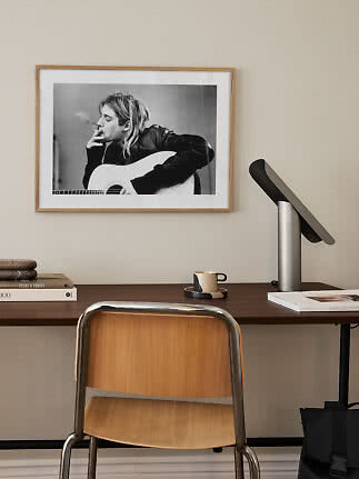 Desk with wooden chair, black table lamp, and framed black-and-white photo on the wall