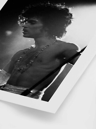 Black-and-white poster showing a close-up of a singer on stage with guitar strap and necklaces