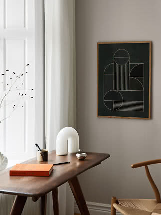 Poster astratto incorniciato con linee geometriche su sfondo scuro sopra un tavolo in legno