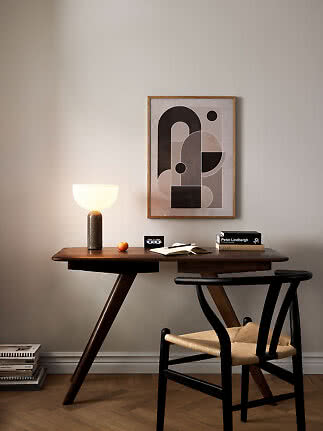 Moderner Schreibtisch mit leuchtender Tischlampe, Stuhl und abstraktem Wandbild