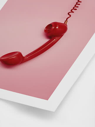 Cornetta telefonica rossa con cavo spiralato su sfondo rosa e bianco