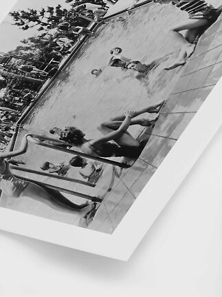 Black-and-white photo of people swimming and playing in an outdoor pool