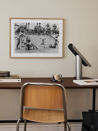 Wooden desk with chair, black table lamp, and framed black-and-white pool photo on the wall