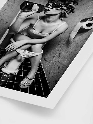 Sort-hvid foto af kvinde på toilet med store solbriller og flaske i hånden