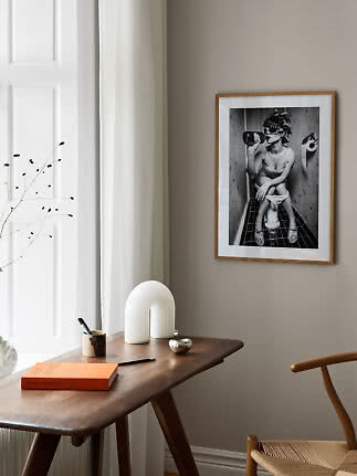 Indrammet sort-hvid foto på beige væg over træbord i lyst, moderne rum