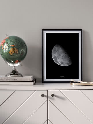 Affiche encadrée de la lune sur un buffet, à côté d’un globe et de livres