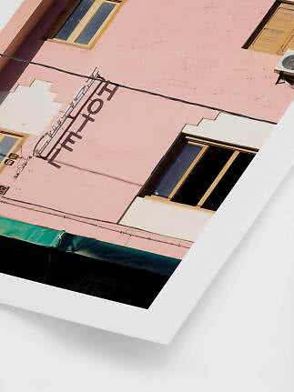 Angled view of a pink hotel building with windows and facade sign