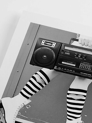 Foto in bianco e nero di una persona con calze al ginocchio a righe e boombox rétro
