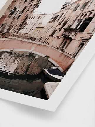 Framed photo of a canal with a small bridge, boat, and pastel buildings