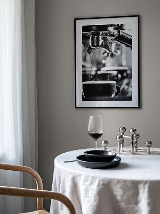 Indrammet sort-hvid kaffefoto over et rundt bord med vinglas og sorte tallerkener