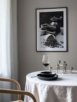 Indrammet sort-hvid plakat af kaffekværn og kaffebønner over et dækket spisebord
