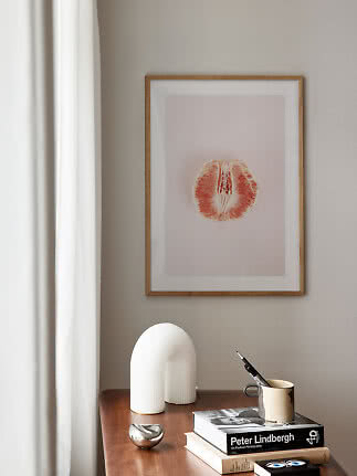 Affiche encadrée d’agrume rose au-dessus d’une table en bois avec livres, lampe et mug