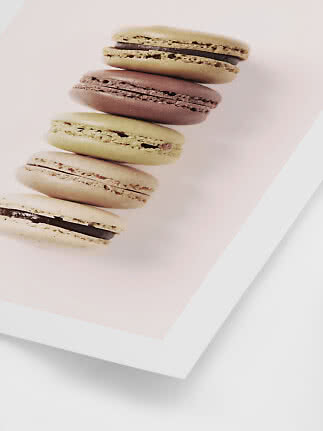 Pila di cinque macarons colorati su sfondo rosa chiaro