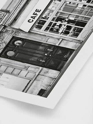 Foto in bianco e nero di una facciata di caffè con grandi finestre e porta doppia scura