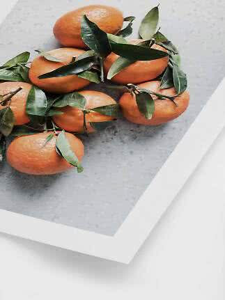 Plusieurs mandarines avec des feuilles vertes sur une surface gris clair