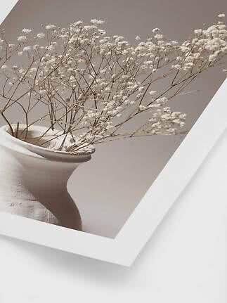 Framed print of white flower stems in a beige vase