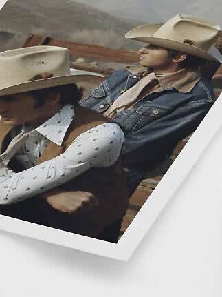 Due uomini con cappelli da cowboy e abiti western siedono vicino a una staccionata in montagna.