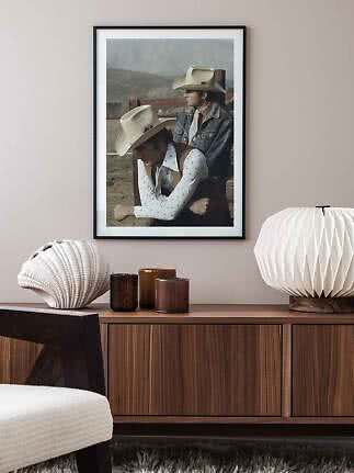 Poster incorniciato con due cowboy con cappelli chiari sopra una credenza in legno