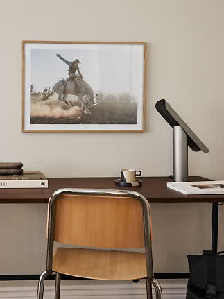 Indrammet rodeofoto over skrivebord med stol, lampe, bøger og kop