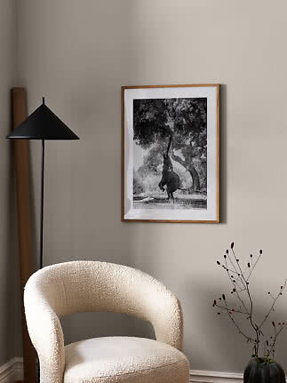 Framed black-and-white elephant print hanging on a beige wall above a cream chair