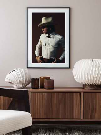 Gerahmtes Poster eines Mannes mit Cowboyhut und gestreiftem Hemd über einem Holzsideboard