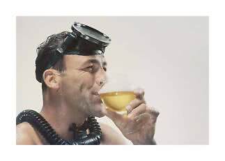 Man met snorkeluitrusting drinkt uit een wijnglas met gouden drank