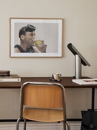 Thuiskantoor met houten stoel, bureaulamp en ingelijste foto aan de muur